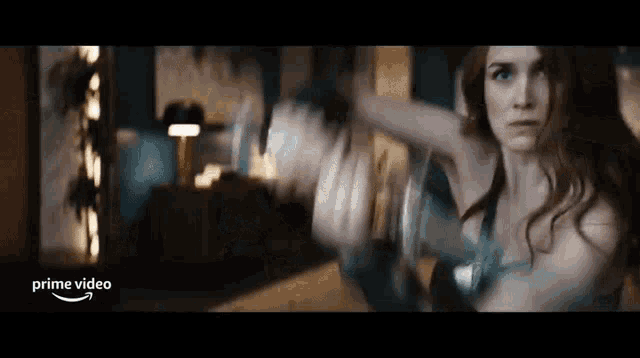 a woman in a superhero costume is holding a sword in a room .