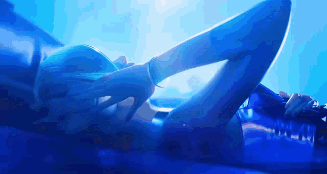 a woman in a bikini is laying on her stomach in a blue light .