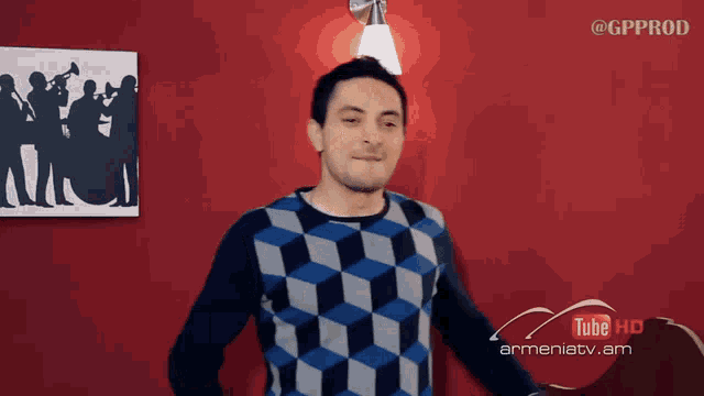 a man stands in front of a red wall with a picture of a band on it and a sign that says tube hd