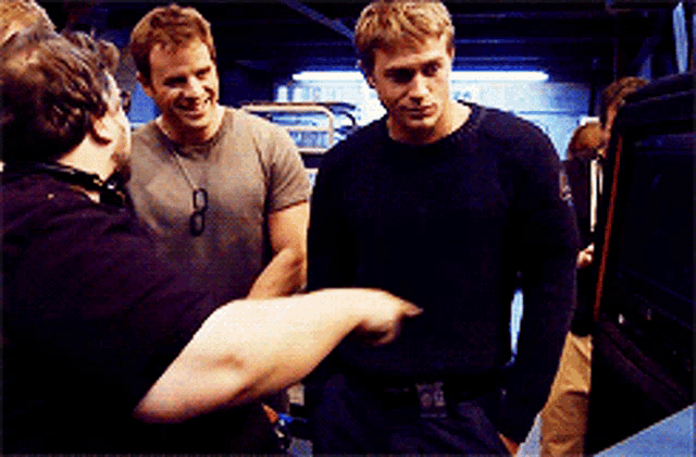 a man wearing a black shirt with the number 8 on it talks to two other men