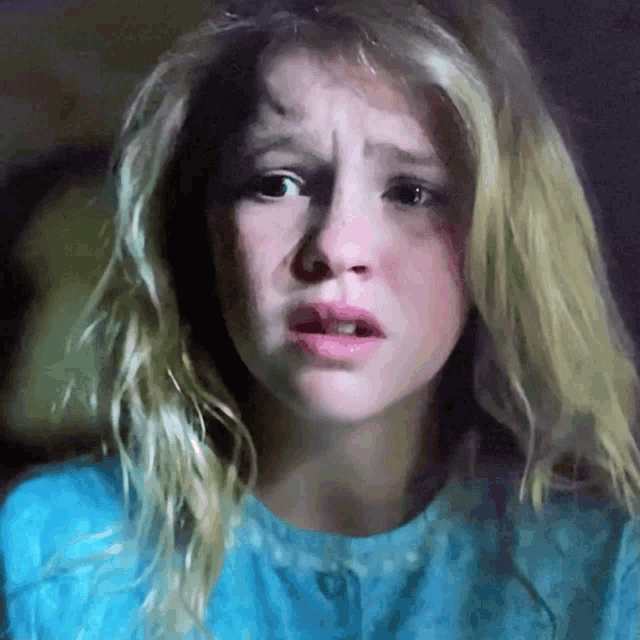 a close up of a woman 's face with a blue shirt on