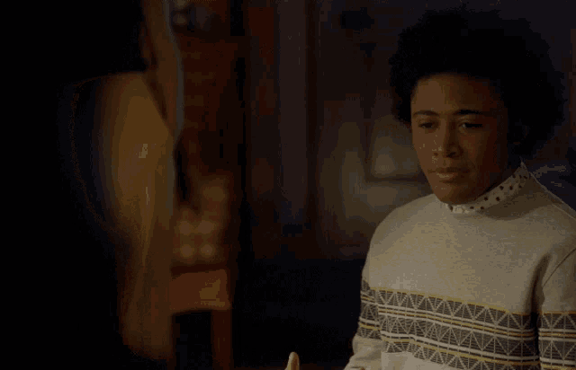 a young man wearing a sweater with a pattern on it