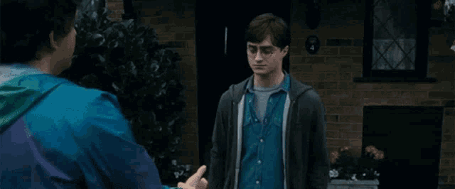 two men are shaking hands in front of a brick building .