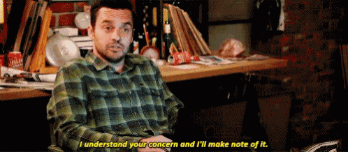 a man in a plaid shirt is sitting at a desk and saying i understand your concern and i 'll make note of