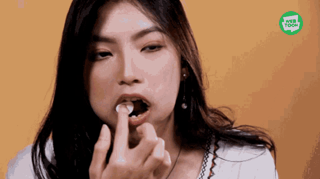 a woman is eating something with a webtoon logo in the background