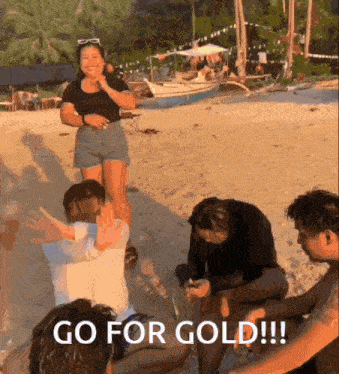 a group of people standing on a beach with the words go for gold