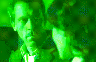 a man and a woman are standing next to each other in a dark room in a green light .
