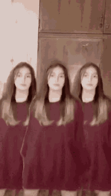 three girls are standing next to each other in a room wearing red sweaters .