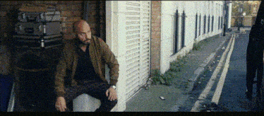 a bald man is sitting on the side of the road