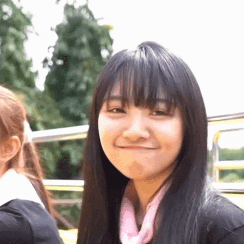 a girl with long black hair is smiling and making a funny face .