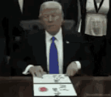 a man in a suit and tie is sitting at a desk with a piece of paper on it .