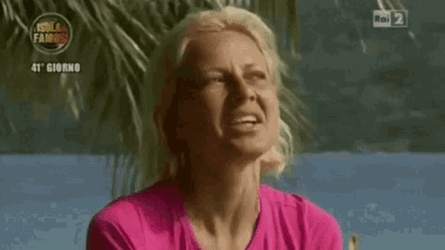 a woman in a pink shirt is making a funny face and saying me ne infischio