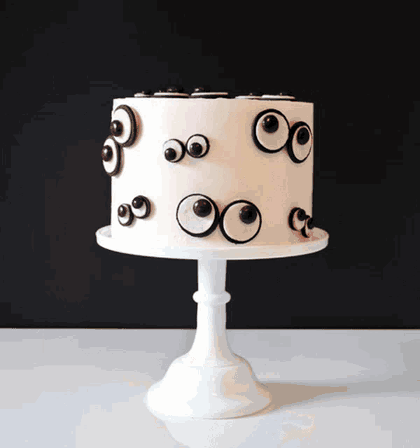 a white cake with chocolate eyes on it on a white cake stand
