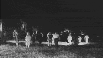 a black and white photo of a group of people walking in a field