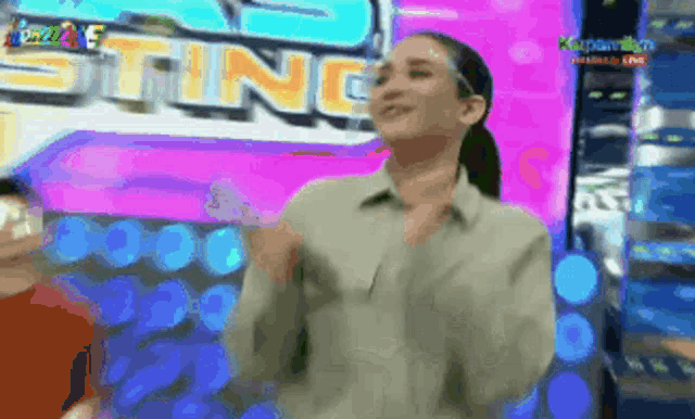 a woman wearing a face shield stands in front of a sign that says sting