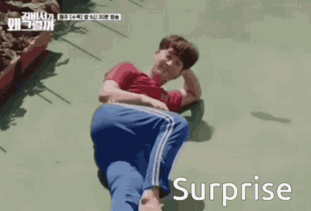 a man in a red shirt and blue pants is laying on the ground with the word surprise written below him