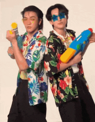 two men in hawaiian shirts are holding water guns .
