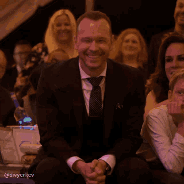 a man in a suit and tie is applauding in a crowd