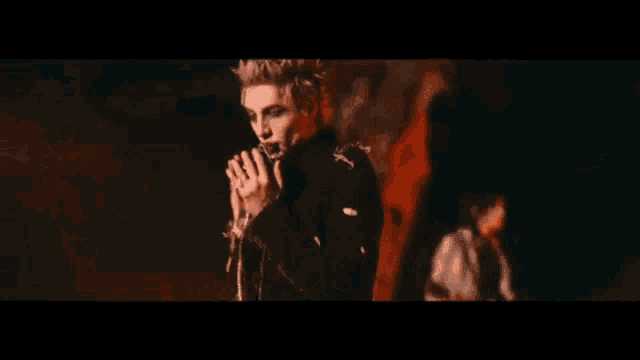 a man singing into a microphone in front of flames