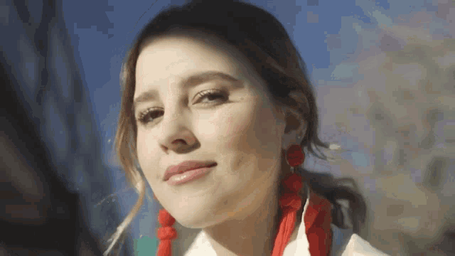 a close up of a woman wearing red earrings and a scarf
