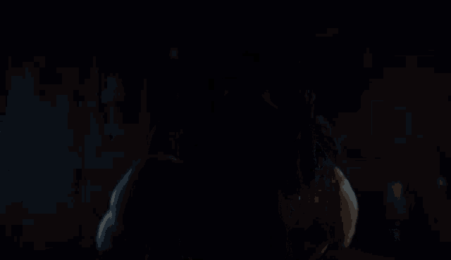 a naked man in a dark room with candles behind him