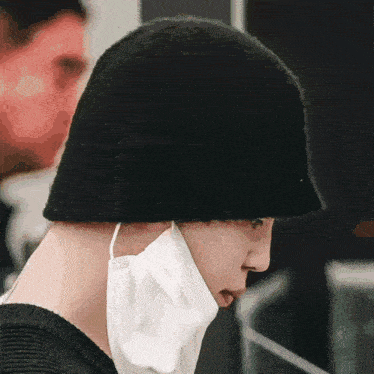 a person wearing a black hat and a white mask