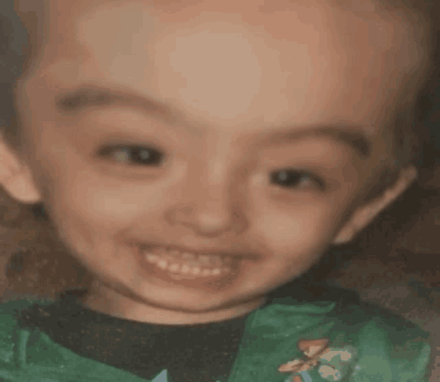 a close up of a child 's face with a green shirt on