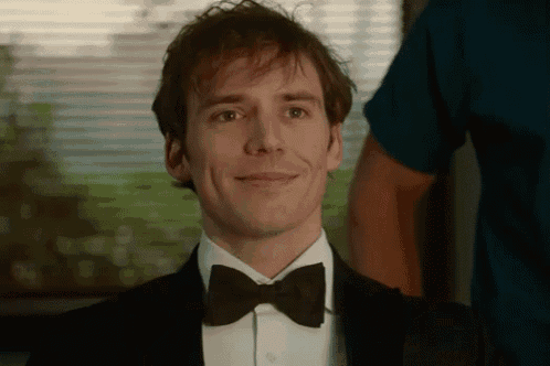 the man is wearing a tuxedo and bow tie and smiling .