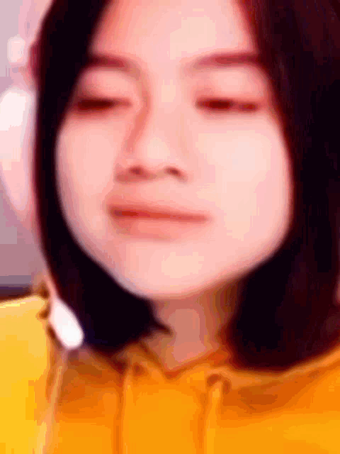 a close up of a woman 's face wearing a yellow hoodie