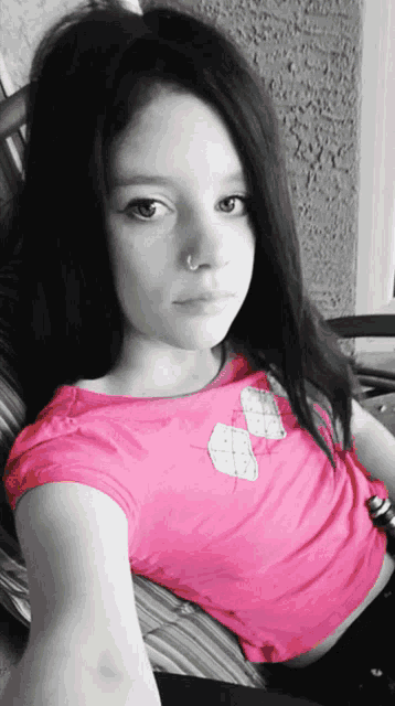 a girl wearing a pink shirt has a nose ring on her nose