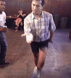a man in a plaid shirt and shorts is dancing in a club .