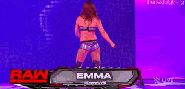 a woman is dancing on a stage in front of a purple wall .