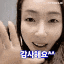 a woman is smiling and waving her hand in a black and white photo with korean writing on it .