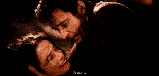 a man and a woman are kissing in a dark room and the man is holding the woman 's head .