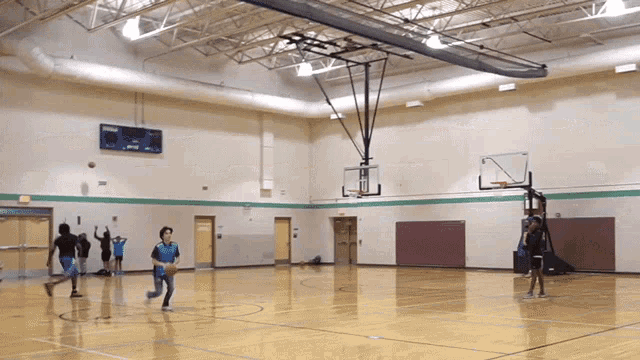 people are playing basketball in a gym with a scoreboard above them