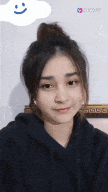 a woman wearing a black hoodie is smiling with a beat.ly sticker in the background