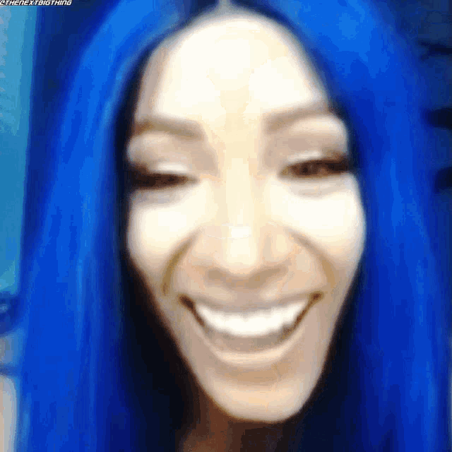 a woman with blue hair is smiling and looking at the camera