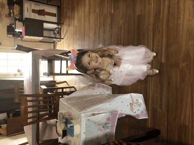 a little girl wearing a pink dress and a unicorn headband
