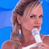 a woman is holding a microphone in her mouth and looking at the camera .