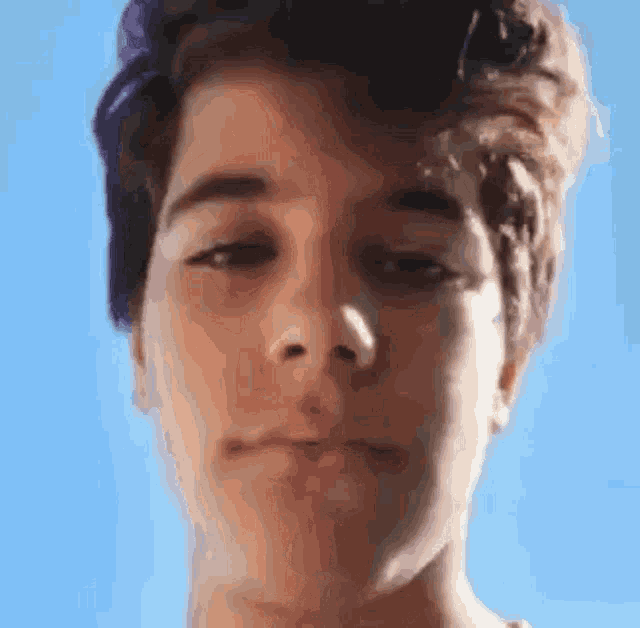 a close up of a man 's face with a blue sky in the background