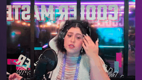 a woman wearing headphones is standing in front of a microphone in a room .