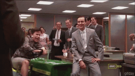 a man in a suit is sitting on a green lawn mower in an office .