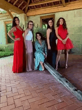 a group of women standing next to each other on a brick sidewalk .
