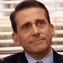 a close up of a man in a suit and tie making a face .