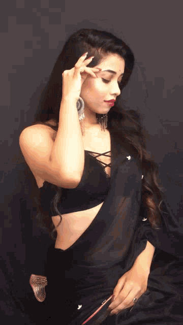 a woman in a black crop top and black saree