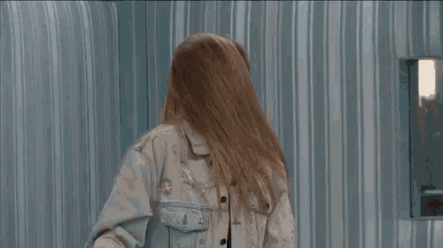 a woman with long hair is standing in front of a striped curtain .