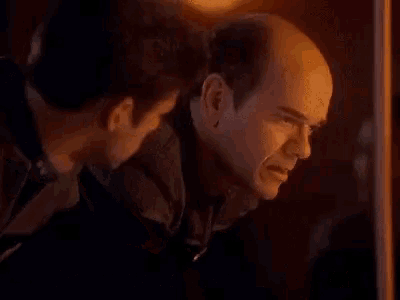 two men are looking at a cell phone and one of them is saying `` i 've got to tweet about this shit `` .