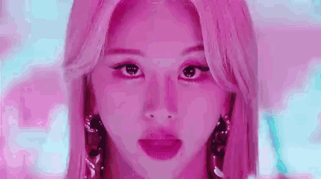 a close up of a woman 's face with pink hair .