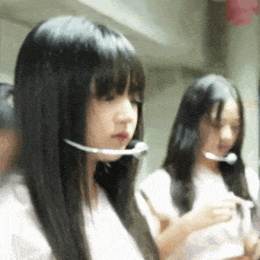 a girl wearing a headset is standing next to another girl with long hair .