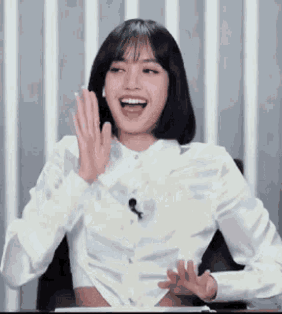 a woman in a white shirt is sitting at a table with her mouth open and laughing .
